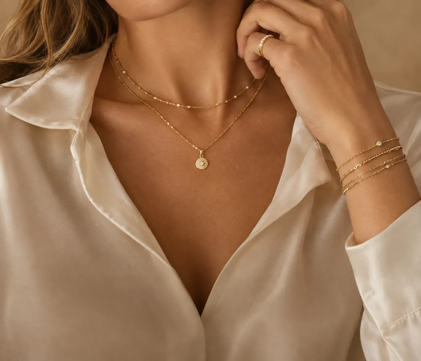 Model wearing layered gold necklaces, ring and bracelets